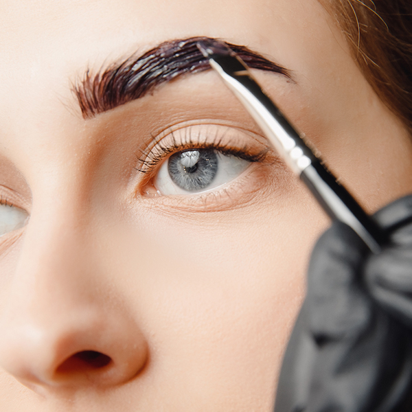 Woman with blue eyes getting her brows shaped and tinted at home