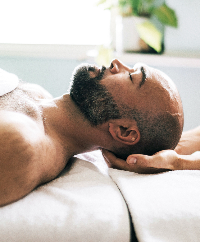 Man lying down on massage table with head supported by hands