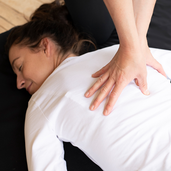 Praticien réalisant un massage shiatsu sur le haut du dos d'une patiente