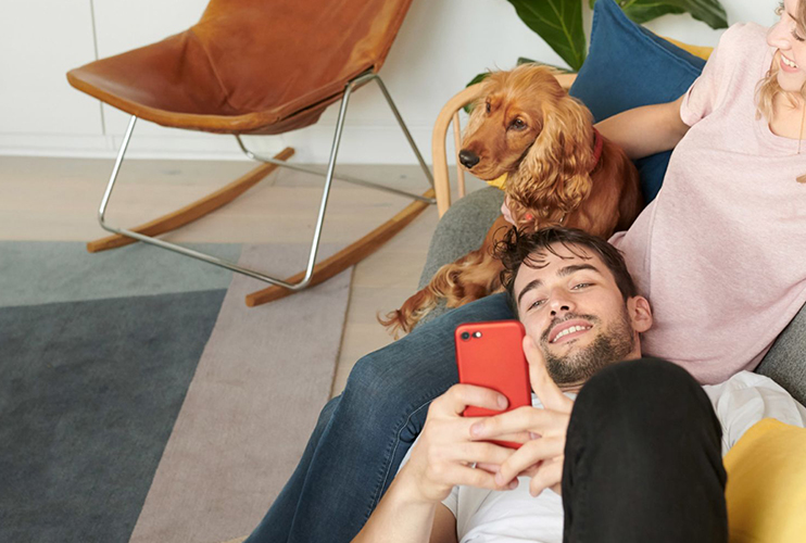 Couple relaxing on a couch with a dog, man has freshly waxed nostrils